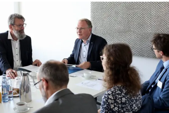 Fünf Personen sitzen um einen Konferenztisch und diskutieren.