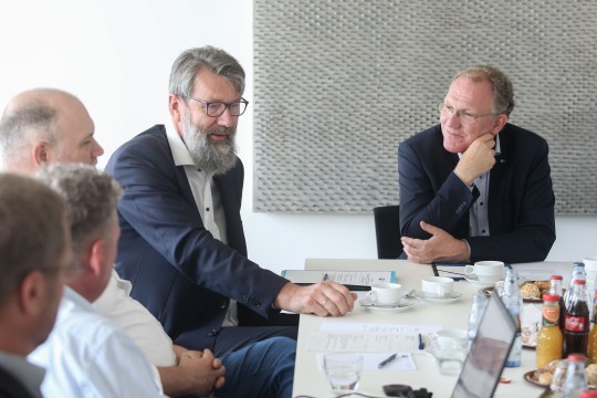 Herr Weiland diskutiert mit einigen Herren an einem Konferenztisch sitzend. 