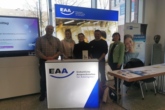 Das Bild zeigt ein Team von fünf EAA-Kolleg*innen an dem EAA Infostand